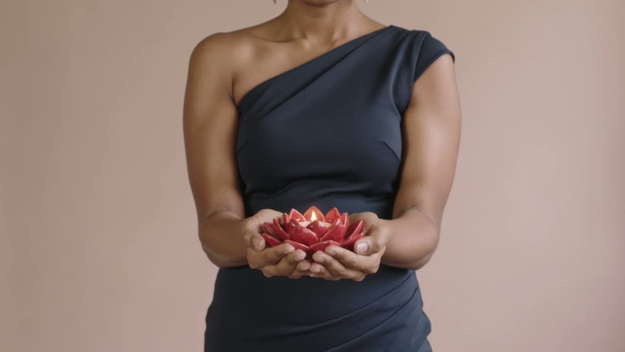 A woman holding a lit lotus candle holder in cupped hands